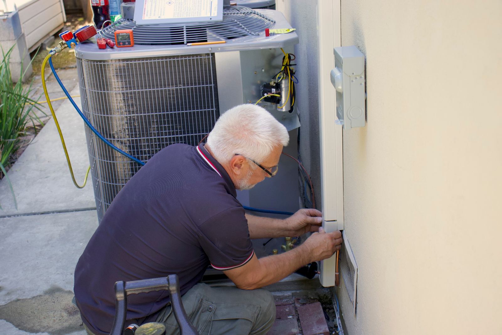 Newly installed Carrier central air conditioning condenser set on a composite pad in a Bay Area backyard during an ABC Service installation.