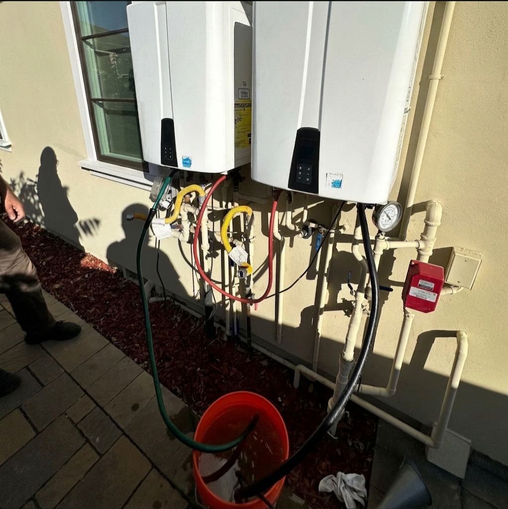 ABC Service descaling two wall-mounted Navien condensing tankless water heaters with isolation valves, pump hoses, and a flush bucket at a Bay Area home.