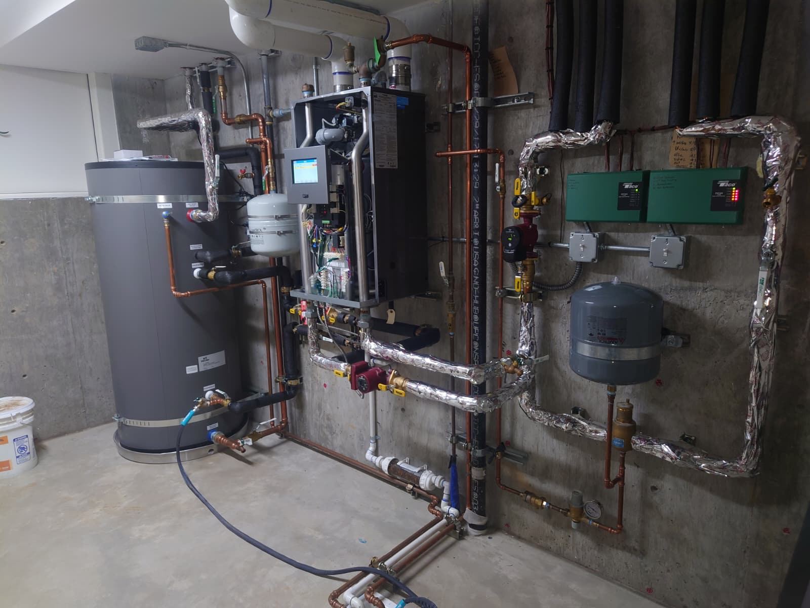 ABC Service hydronic mechanical room with indirect tank, condensing boiler, ECM circulators, expansion tanks, and Taco zoning controls.