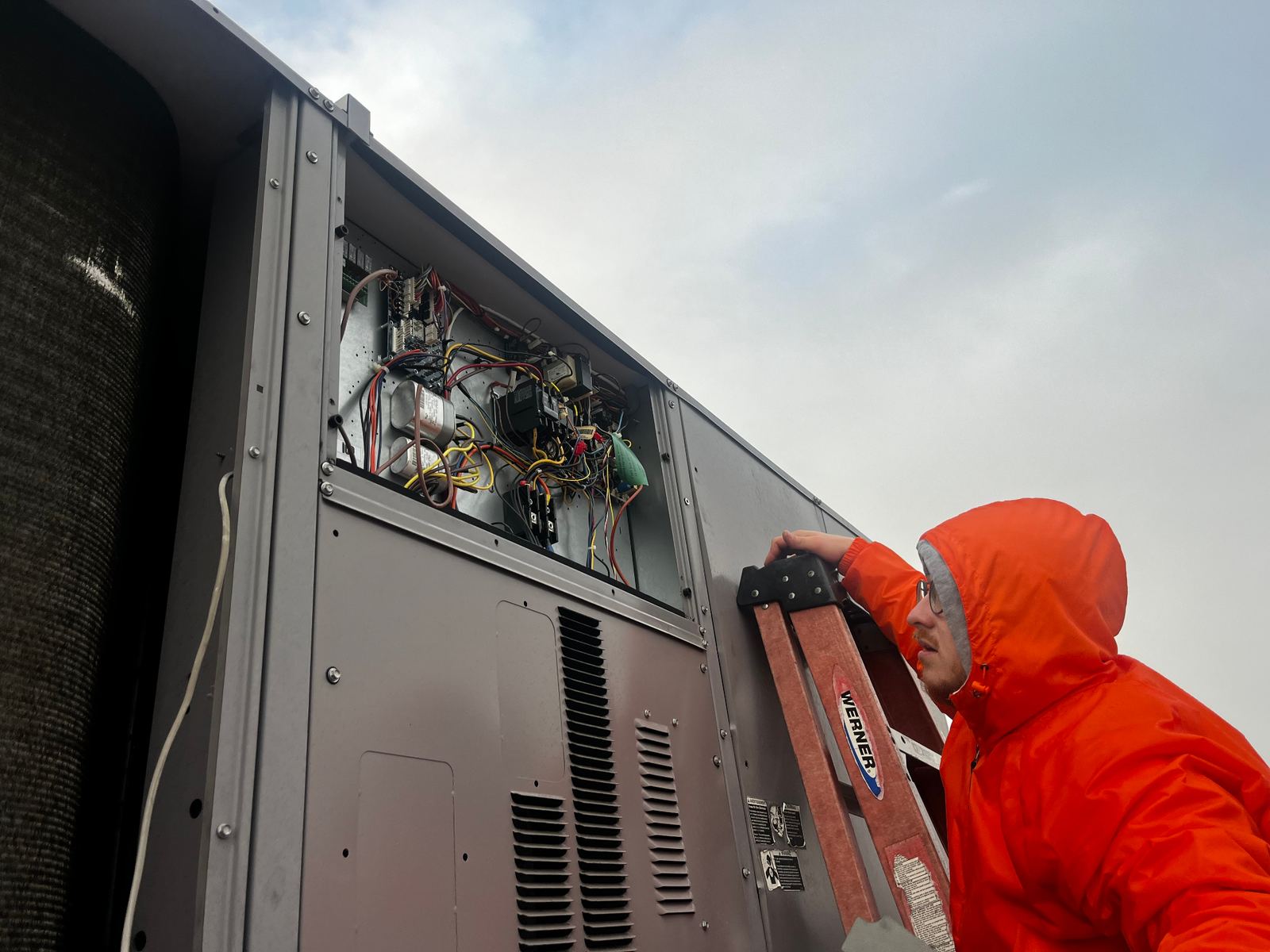 ABC Service technician diagnosing the open control panel of a commercial rooftop packaged HVAC unit.