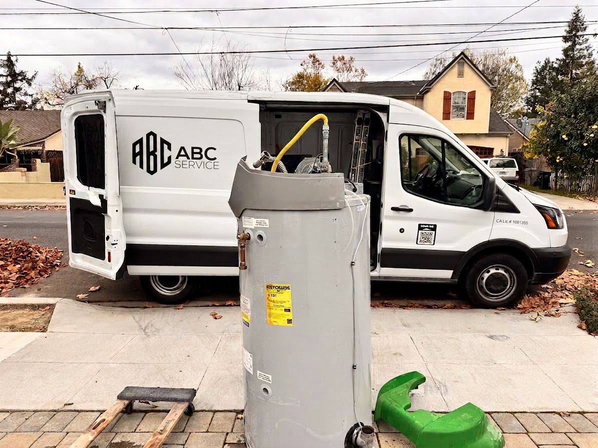 ABC Service van parked curbside with an old tank water heater removed and ready for tank-to-tankless conversion in a Bay Area neighborhood.