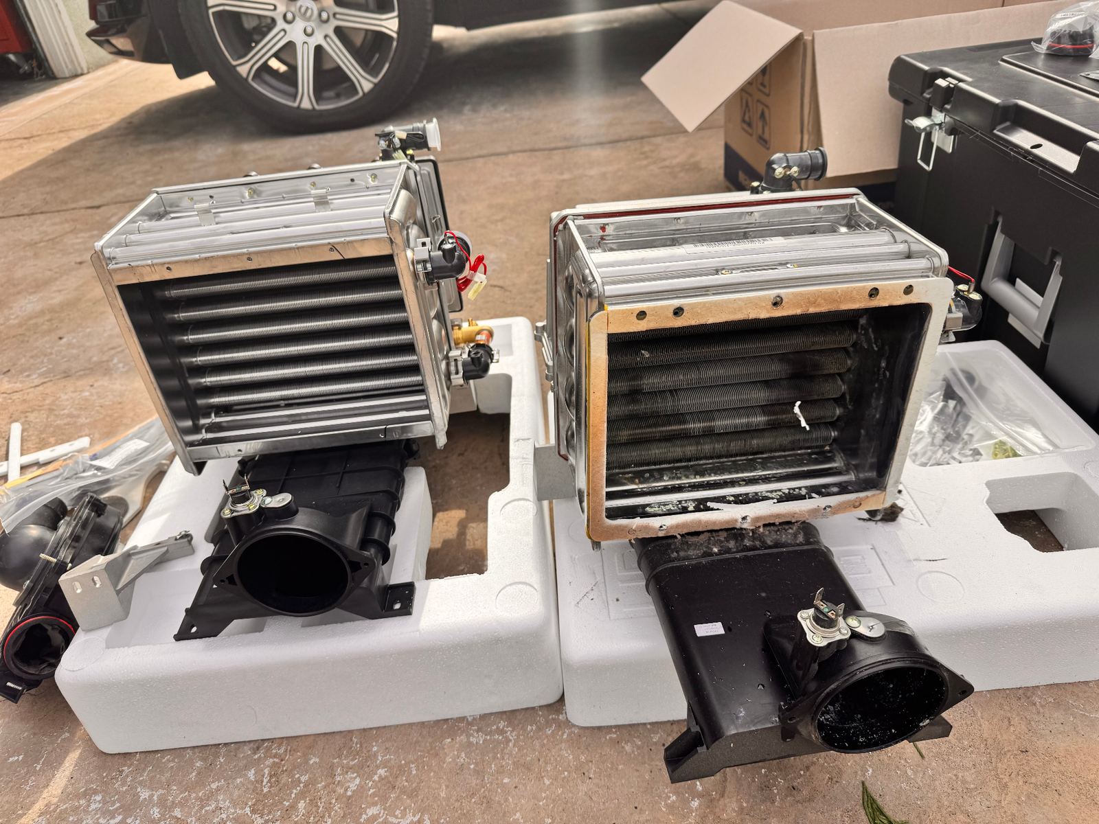 Two Navien condensing heat exchangers staged side by side for warranty evaluation — one new replacement unit and one failed unit with scale buildup — documented by ABC Service for a manufacturer warranty claim.